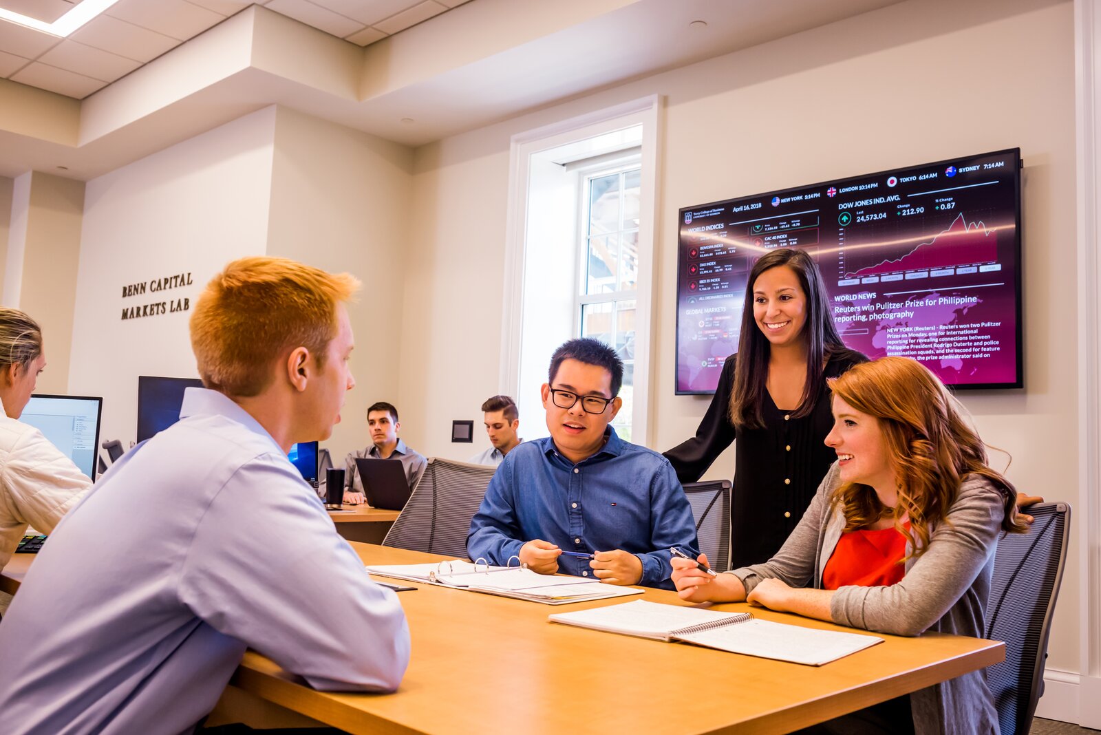 Terry students collaborating around a worktable in the Benn Capital Markets Lab, with the engraved lab signage visible on the wall